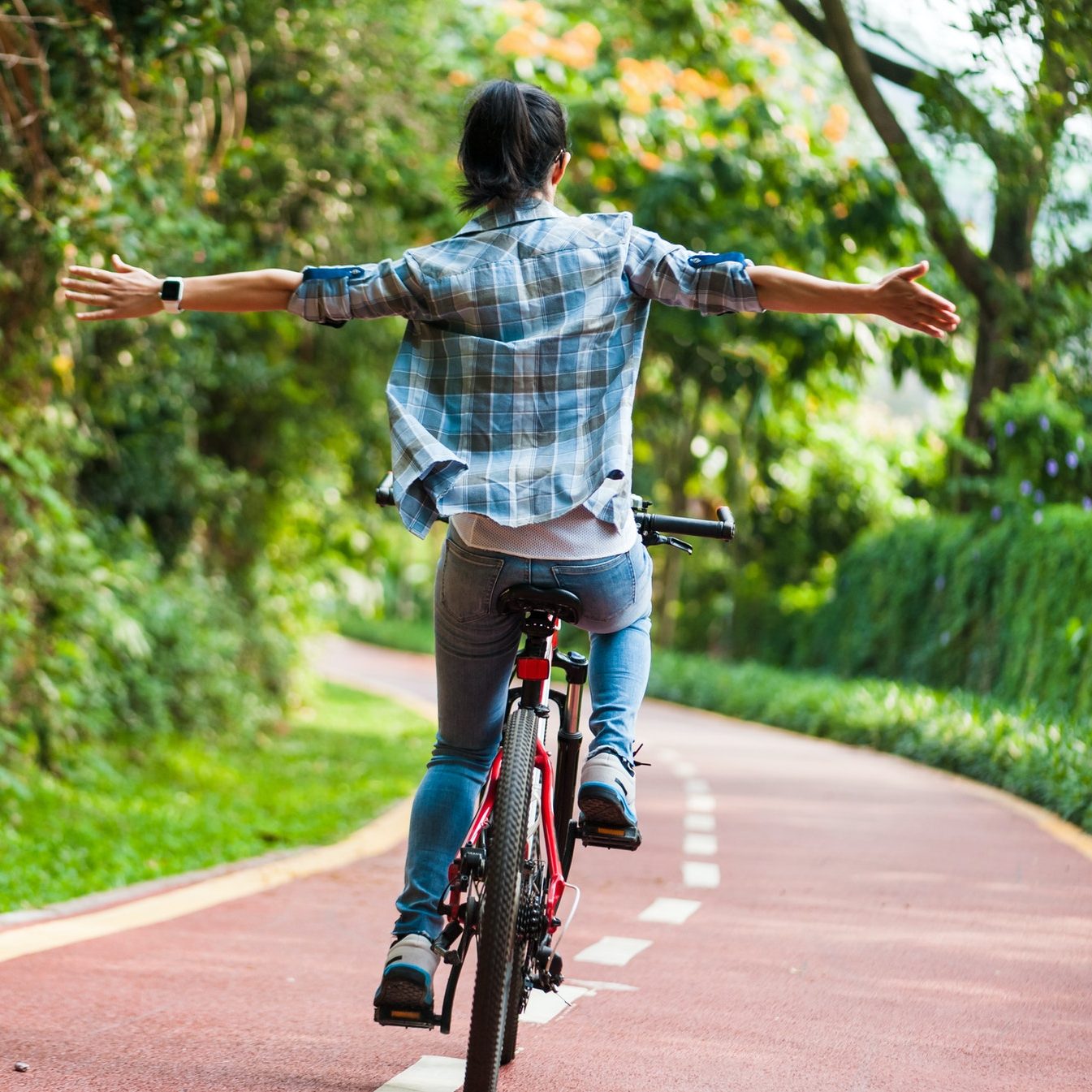 Woman riding mountain bike with her arms outstretched